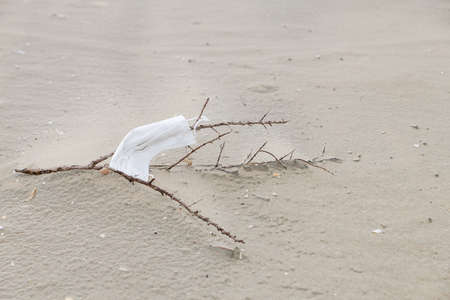 A face mask for protection during the Covid-19 pandemic is left behind on the beach causing...