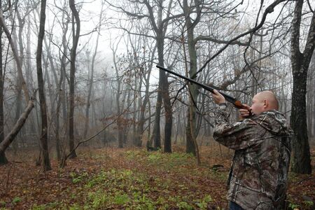 hunter with a gun in the misty autumn forest