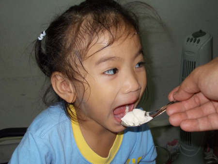 Girl feeding with a spoonの写真素材