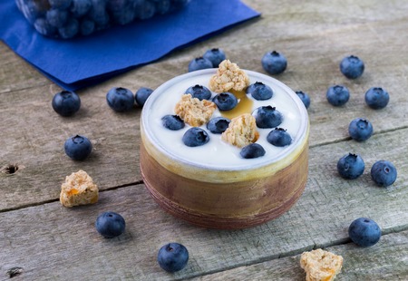 White yogurt with blueberries and cereals in ceramic bowl.の写真素材