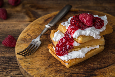 Belgian waffles with raspberries and double cream on rustic table.の写真素材