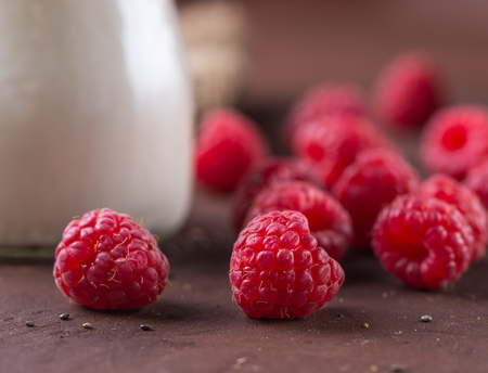Detail of raspberries on rustic table with part of white yogurt jar .の写真素材