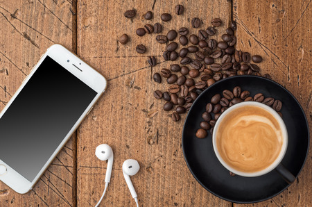 Top View of coffee cup with mobile phone and headphones on rustic background.の写真素材