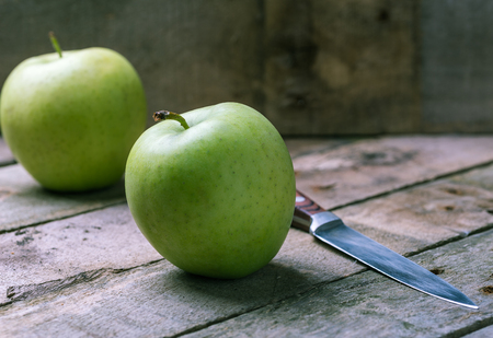 Green apple with knife on wooden natural desk.の写真素材