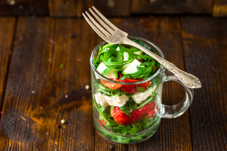 Fresh vegetable strawberry salad in glass jar on natural rustic desk.の写真素材