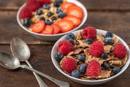 Granola chips with blueberries and raspberries in white bowl.の写真素材