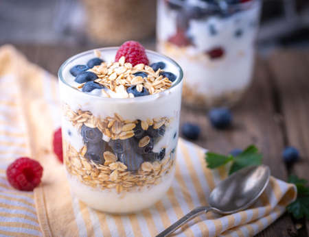 White yogurt in glass jar with fruits on yellow napkin.の写真素材