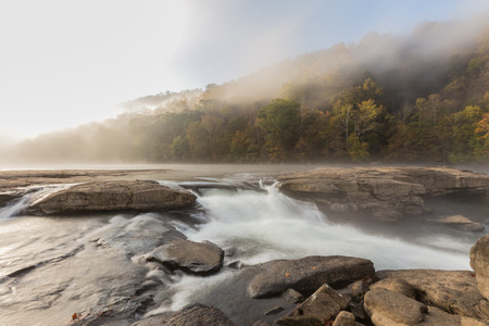 Tygart River cascades over rocks at Valley Falls State Park in Fairmont, West Virginia, fog over the river in the morning at sunriseの写真素材