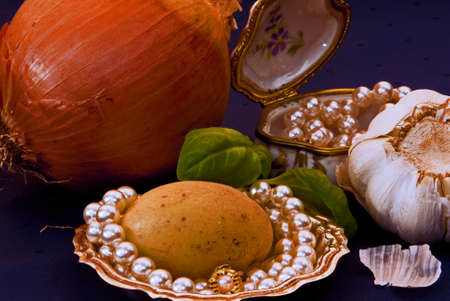 Onions, garlic and potatoes staying togheter with pearls and jewelry. Made in Studio. Normal life ist more and more expensiveの写真素材