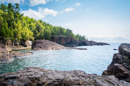 Lake Superior, with green trees and gray cliffs of Presque Isle Park.の写真素材
