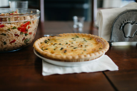Baked quiche and bowl of orzo salad on a tableの写真素材