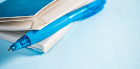Blue pen in a notebook on blue backgroundの写真素材