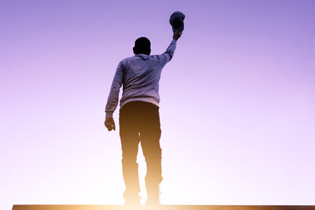 man portrait holding a cap and sunset backgroundの写真素材