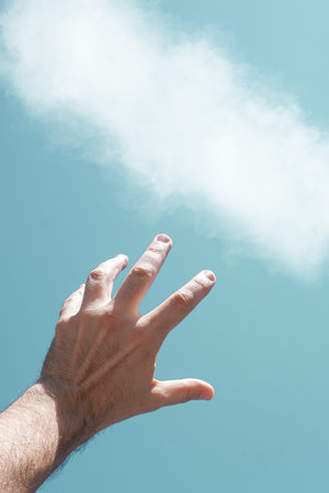 hand up in the air playing with the sunlight, blue backgroundの写真素材