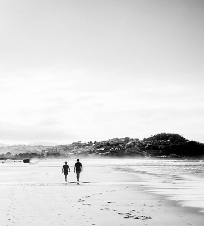 two people walking on the beach at sunsetの写真素材