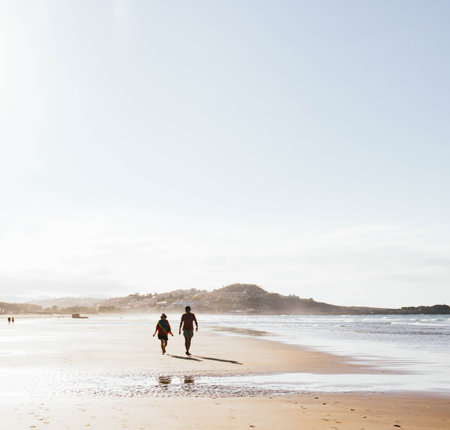 two people walking on the beach at sunsetの写真素材