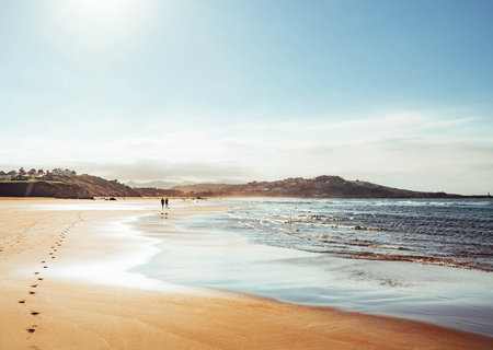 two people walking on the beach at sunsetの写真素材