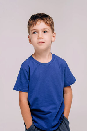 Half-length emotional portrait of caucasian teen boy wearing blue t-shirt. Surprised teenager looking at camera. Handsome happy child, isolated on white background.の写真素材