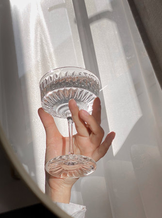 A glass with a drink in a woman's hand in the sunlight.の写真素材