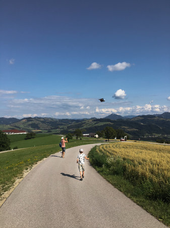 Dad and son are flying a kite in the village.の写真素材