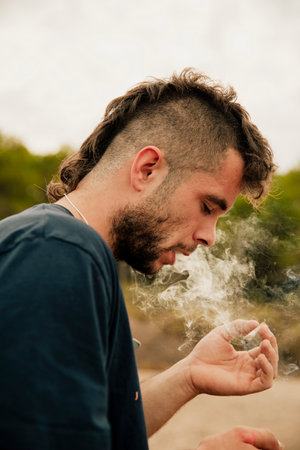 Young guy smoking a marijuana joint while staring at itの写真素材