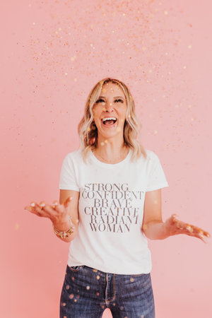 standing woman laughs while throwing gold glitterの写真素材