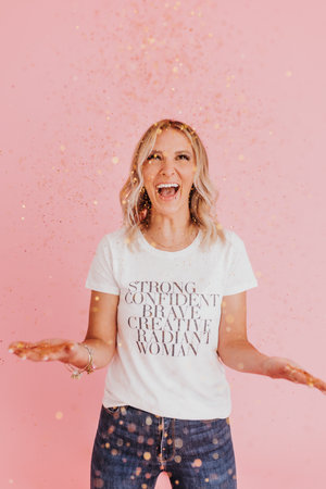 Smiling woman looks at camera while throwing gold glitterの写真素材