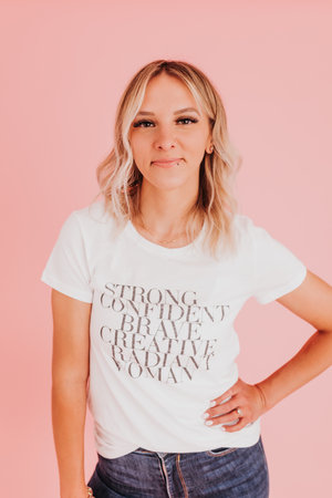 Woman stands confidently against pink backdrop looking at cameraの写真素材