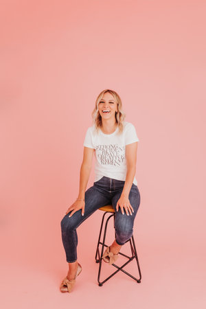 Female sits confidently on stool against pink studio backdropの写真素材