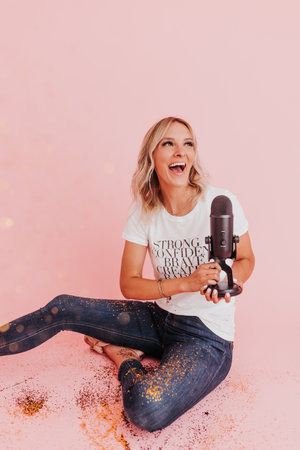Woman sits on floor covered in glitter holding podcast microphoneの写真素材