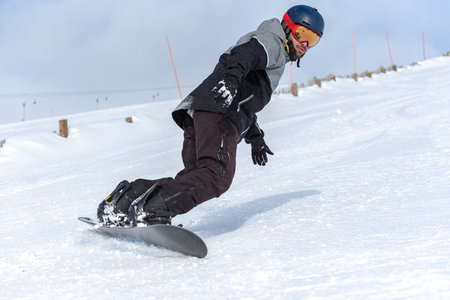 Young man snowboarding on the slopes of a ski resortの写真素材