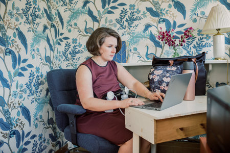 Caucasian mother with short brown hair pumps at desk.の写真素材