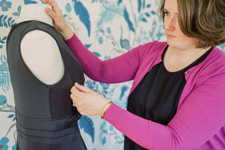 Caucasian woman zips up bust area of black dress for pumping mothers.の写真素材