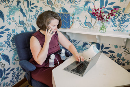 Working mom pumps at desk while talking on the phone.の写真素材