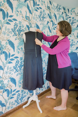 Short-haired Caucasian woman zips up black professional dress on bust.の写真素材