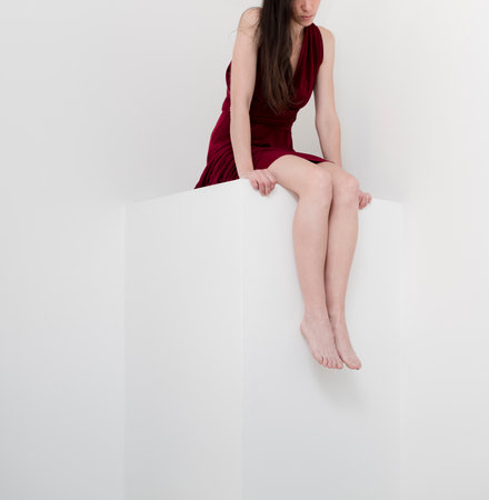 Surreal portrait of sitting woman on minimal white spaceの写真素材