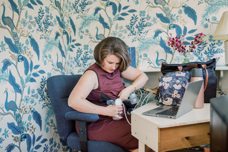Short-haired Caucasian mother inserts breast pump at desk.の写真素材