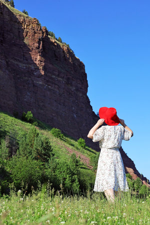 A woman in a hat on the background of the red mountain Shamanic cliffの写真素材