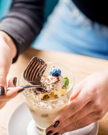 Delicious dessert in a glass in female handsの写真素材