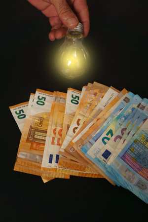 lighted light bulb with euro banknotes in the backgroundの写真素材