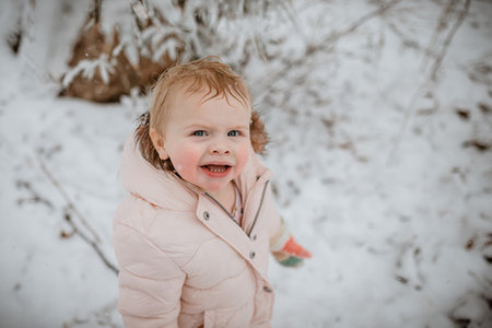 Young female child on a winter day in the snow cold with no hatの写真素材