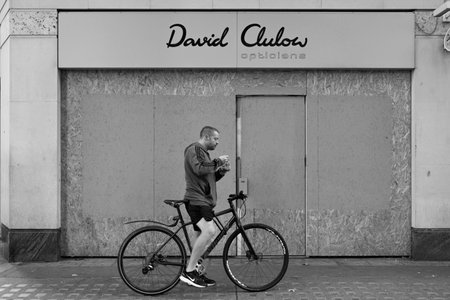 Cyclist eating ice cream in the streets of Victoria Streetのeditorial素材
