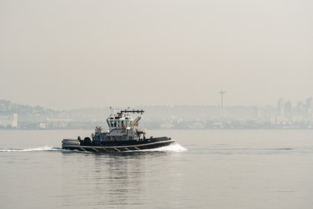 A tug boat in front of a hazy Seattle skylineのeditorial素材
