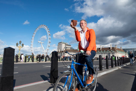 Tourist man cycling and photographing around Westminster Bridgeのeditorial素材