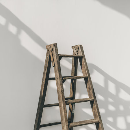 A rustic wooden ladder against a clean white wall, casting intriguing shadows.の素材