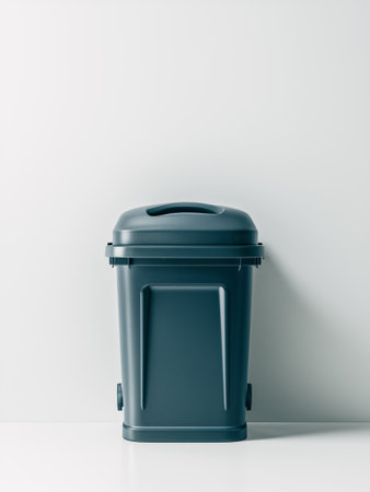 A modern dark gray trash bin against a minimalist white wall, showcasing a clean and organized environment.の素材