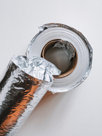 Close-up of a roll of aluminum foil with partially unwrapped layers, showcasing its shiny surface.の素材