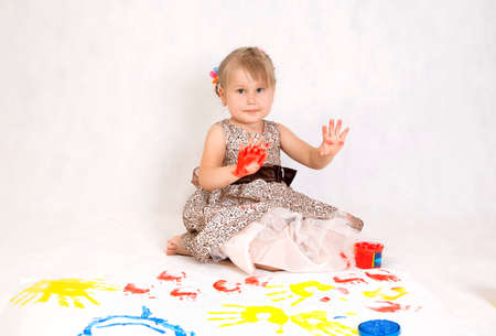 Little beautiful girl draws paints, hands in the paintの写真素材