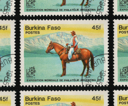 BURKINA FASO - CIRCA 1985: A used postage stamp printed in Burkina Faso from the "International Stamp Exhibition "Argentina '85" - Buenos Aires - Horses" issue, showing a man riding a horse.のeditorial素材