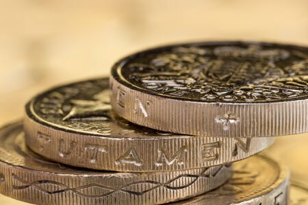Close up of British money, pound coins precariously balanced.